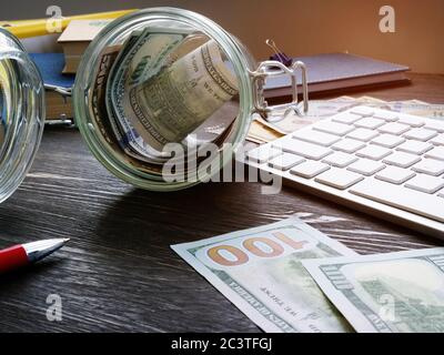 Glas mit Geld auf dem Schreibtisch. Sparkonzept und Konzept der persönlichen Finanzen. Stockfoto