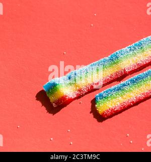 Fragment der farbigen Marmelade auf dem roten Hintergrund. Natürliche Regenbogenfarben Marmelade Süßigkeiten. Platz kopieren, leere Vorlage für Text Stockfoto