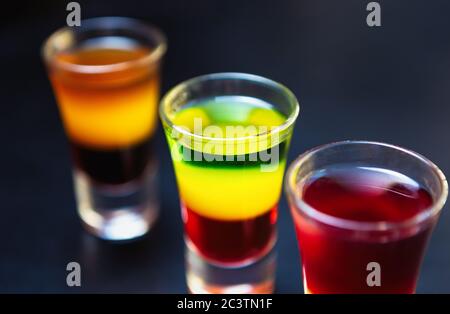 Drei mexikanische Tequilla-Shots mit mehrfarbigen alkoholischen Getränken auf dem Tisch serviert bei Party im Nachtclub.Genießen Sie starke Schnaps mit goldenem Rum in Stockfoto