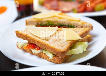 Köstliche Club Sandwiches mit Gourmet-Zutaten zum Frühstück im Diner Cafe gekocht.Parmesan Käse auf Toast Brot mit rotem Lachs Fischfille serviert Stockfoto