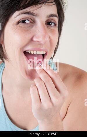 Eating Disorder Concept - Studioaufnahme eines weiblichen Models in ihren 20er Jahren, das eine Vitaminpille auf weißem Hintergrund verschluckt Stockfoto
