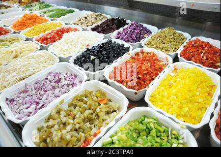 Schneiden Sie die Zutaten für den Salat an einer Salatbar Stockfoto