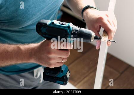 Mann, der zu Hause Renovierungsarbeiten macht, Bohren mit einem Schraubendreher. Gruppe von Reparaturwerkzeugen auf weißem Hintergrund. Stockfoto