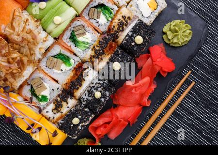 Verschiedene Arten von asiatischen Sushi-Rollen auf grauem Hintergrund. Nahaufnahme von oben. Stockfoto