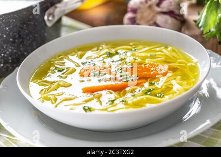 Hühnersuppe Brühe in einem Teller Karotte Zwiebel Sellerie Kräuter Knoblauch und frisches Gemüse Stockfoto