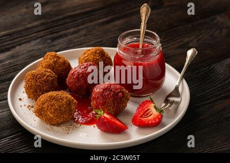 Hausgemachte Quark-Bälle, ungarische süße Nachspeise mit Erdbeermousse serviert. Stockfoto