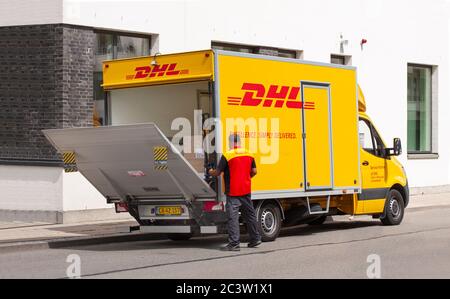 Liefermann in uniform öffnenden Heckklappenlader auf einem DHL-LKW. Kurier-, Paket- und Expresspost-Service. Pakete im Fahrzeug sichtbar. Kopenhagen Stockfoto