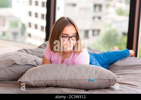 Nettes Teenager-Mädchen auf dem Bett in ihrem Zimmer entspannend Stockfoto