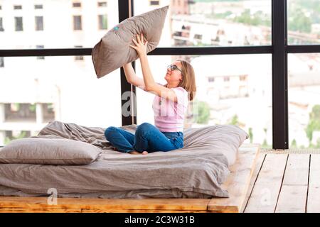 Nettes Teenager-Mädchen auf dem Bett in ihrem Zimmer Spaß mit Kissen Stockfoto