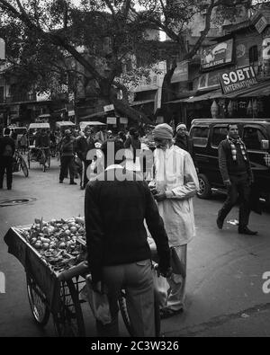 Delhi, Indien - Alter Mann, der Früchte auf dem Straßenmarkt in Paharganj kauft, geschäftige Backpacker-Enklave voller Budget-Gästehäuser und winzigen Geschäften. Stockfoto