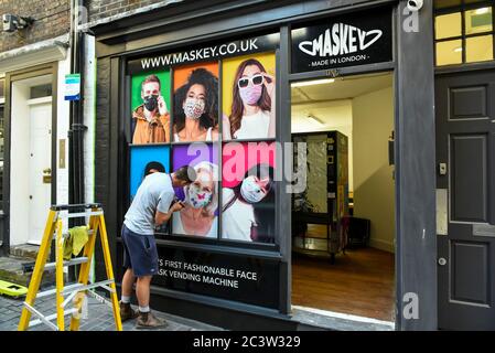 London, Großbritannien. 22. Juni 2020. Ein Dekorateur malt das Äußere eines Pop-up-Stores in der Carnaby Street, in dem ein Verkaufsautomat untergebracht ist, der Facemasken von dem Londoner Unternehmen Maskey an die Öffentlichkeit verkauft. Das neu gegründete Unternehmen wurde von Unternehmer Adam Freeman gegründet, um der Nachfrage nach erschwinglichen Gesichtsmasken aus Großbritannien während der laufenden Coronavirus-Pandemie gerecht zu werden. Es installiert die ersten modischen Verkaufsautomaten für Gesichtsmasken in Großbritannien an Standorten in London, die weiter ausgebaut werden sollen. 10% des Gewinns aus jedem Facemask-Verkauf wird an eine Wohltätigkeitsorganisation gespendet, die das NHS unterstützt. Quelle: Stephen Chung / Alamy L. Stockfoto