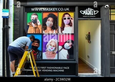 London, Großbritannien. 22. Juni 2020. Ein Dekorateur malt das Äußere eines Pop-up-Stores in der Carnaby Street, in dem ein Verkaufsautomat untergebracht ist, der Facemasken von dem Londoner Unternehmen Maskey an die Öffentlichkeit verkauft. Das neu gegründete Unternehmen wurde von Unternehmer Adam Freeman gegründet, um der Nachfrage nach erschwinglichen Gesichtsmasken aus Großbritannien während der laufenden Coronavirus-Pandemie gerecht zu werden. Es installiert die ersten modischen Verkaufsautomaten für Gesichtsmasken in Großbritannien an Standorten in London, die weiter ausgebaut werden sollen. 10% des Gewinns aus jedem Facemask-Verkauf wird an eine Wohltätigkeitsorganisation gespendet, die das NHS unterstützt. Quelle: Stephen Chung / Alamy L. Stockfoto