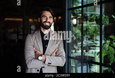 Porträt eines Geschäftsmannes mit Jacke, die im Restaurant steht. Stockfoto