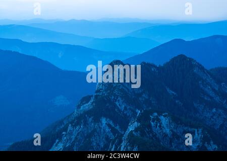 Spektakuläre Aussicht auf blaue Bergketten Silhouetten und Nebel in Tälern. Die Julischen Alpen, Nationalpark Triglav, Slowenien. Blick vom Berg Slemenova Stockfoto