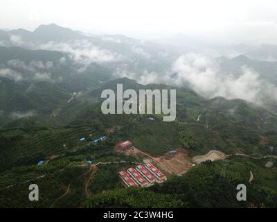 (200622) -- HEFEI, 22. Juni 2020 (Xinhua) -- Luftfoto vom 20. Juni 2020 zeigt eine Umsiedlungsstelle, wo Cai Qiyan und ihre Eltern im Dorf Gaowan im Bezirk Jinzhai, ostchinesische Provinz Anhui, leben. Cai Qiyan genießt den Blick auf die fließenden Wolken von einer der Teeplantagen auf den Bergen. Aber der Spaß war auch ein Luxus für den 15-Jährigen, der mit angeborener Skoliose diagnostiziert wurde. Von Anfang an hatte Qiyan es extrem schwierig gefunden, ihre Wirbelsäule aufrecht zu halten. In der Tiefe des Dabie-Gebirges musste Qiyan zwei Stunden auf dem Weg zur Schule und zurück nach Hause verbringen Stockfoto