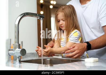 Vater und Tochter waschen sich die Hände über dem Waschbecken in einer Küche Stockfoto