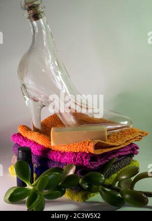 Glasschuh und Seife auf Facecloths verschiedener Schattierungen mit natürlicher grüner Pflanze Stockfoto