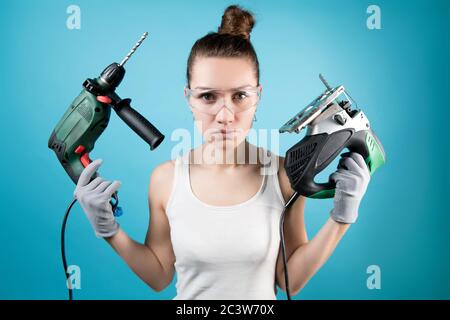 Mädchen hält eine Bohrmaschine und ein elektrisches Puzzle in ihren Händen. Stockfoto