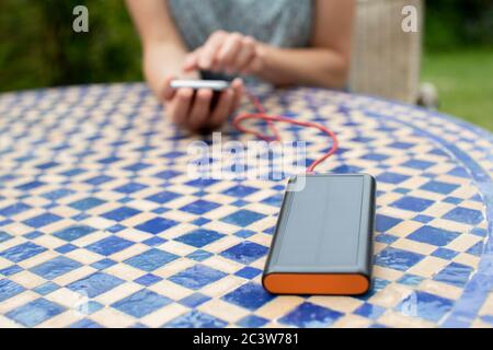 Frau Lädt Handy Im Freien Zu Hause Mit Tragbaren Solar Power Bank Stockfoto