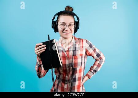 Frau hält in ihrer Hand ein Buch, in das die Der Stecker des Kopfhörers klemmt Stockfoto