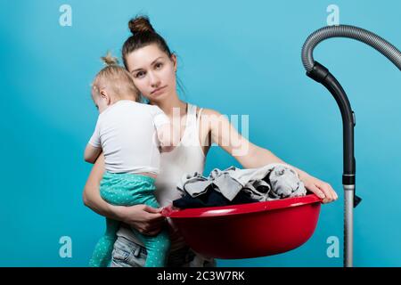 Mutter hält eine kleine Tochter und mit ihr eine große Waschbecken mit Wäsche im Waschgang Stockfoto