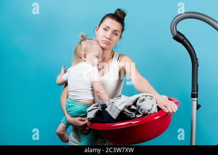 Mama schaut traurig auf die Kamera, in ihren Armen ist ein kleines Kind und ein Haushalt Stockfoto