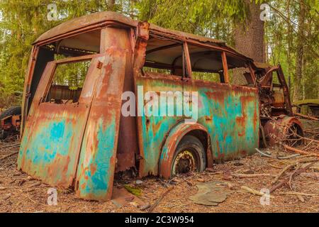 Wrack eines bunt verrosteten alten Transportbusses in einem Wald Stockfoto