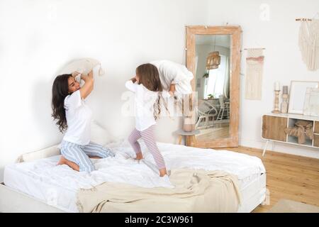 Mutter und ihr Mädchen kämpfen um Kissen. Frohe Familienspiele. Mutter und ihre niedlichen Vorschule Tochter Kind Mädchen im Pyjama spielen und umarmen Stockfoto