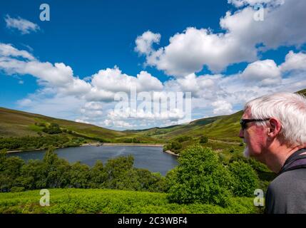 Senior Mann bewundernde Aussicht auf Scottish Water Hopes Reservoir, Lammermuir Hills, East Lothian, Schottland, Großbritannien Stockfoto