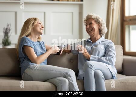 Millennial Tochter trinkt Tee mit älteren Mutter während angenehme Gespräch Stockfoto
