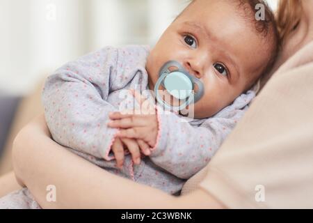 Nahaufnahme Porträt von niedlichen Mixed-Race Baby saugen auf Schnuller während in Mütter Arme, kopieren Raum Stockfoto