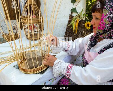 Woronesch, Russland - 05. September 2019: Frau in Nationaltracht webt einen Korb Stockfoto