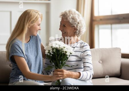 Erwachsene Tochter bereiten Blumen für die alte Mutter gratuliert zum Geburtstag Stockfoto