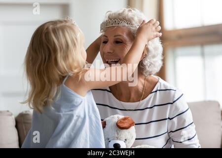 Enkelin setzt auf ältere Großmütter Kopf Krone spielen zusammen Stockfoto