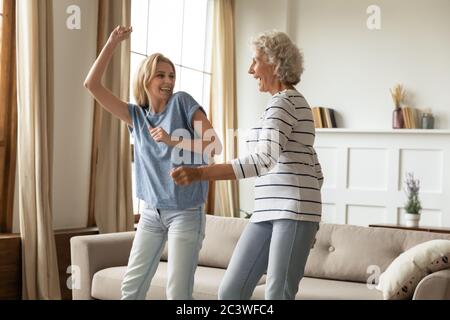 Erwachsene Enkelin und ältere Großmutter tanzen zu Hause fühlt sich glücklich Stockfoto