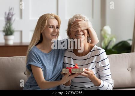 Erwachsene fürsorgliche Tochter machen Überraschungsgeschenk für ältere Mutter Stockfoto