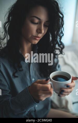 Hübsche Brünette Frau im Morgenbett mit Büchern und Kaffee Stockfoto