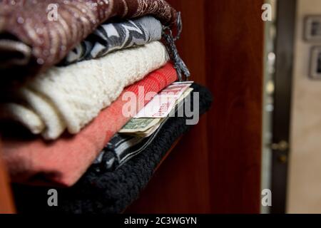 Euro und Dollar ragen aus einem Kleiderhaufen In einem Kleiderschrank Stockfoto