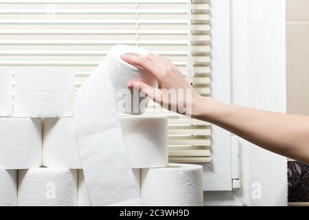 Eine Hand nimmt eine Rolle Toilettenpapier vom Fensterbank in der Toilette Stockfoto