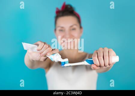 Eine junge Frau quetscht Zahnpasta auf eine Bürste, die sie Hält vorne Stockfoto