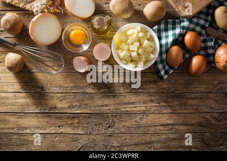 Spanische Omelette Tortilla Zutaten: Eier, Kartoffeln und Zwiebeln auf Holzhintergrund. Draufsicht. Speicherplatz kopieren Stockfoto