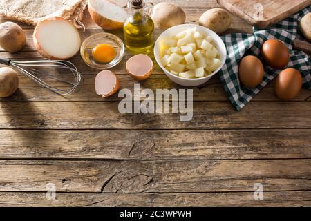 Spanische Omelette Tortilla Zutaten: Eier, Kartoffeln und Zwiebeln auf Holzhintergrund. Draufsicht. Speicherplatz kopieren Stockfoto