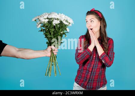 Das Mädchen ist angenehm überrascht, die Hand eines Mannes reicht ihr einen Blumenstrauß aus Stockfoto