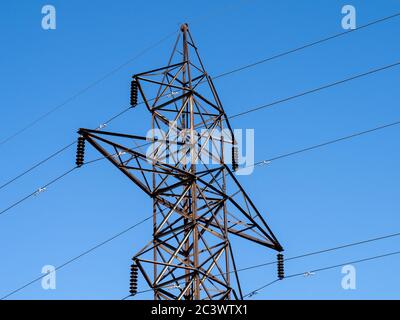 Der obere Teil eines Hochspannungsverteilerturms für Wasserkraft auf einem blauen Himmel Stockfoto