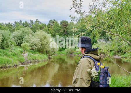 Aktiver Mann in Moskitoanzug mit Rucksack beim Wandern in der Nähe der Taiga Fluss in einem sibirischen Wald, Russland. Alleinreisen, Lifestyle, inländisches Tourismuskonzept Stockfoto