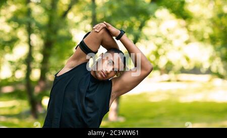 Cool schwarz Kerl Stretching seinen Arm nach dem Training im Park, freien Platz Stockfoto