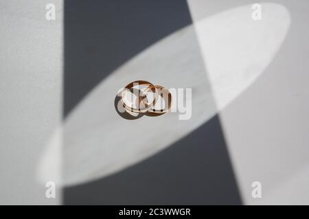 Eheringe liegen auf weißem Hintergrund. Spiel der Schatten Stockfoto
