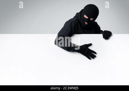 Maskierter Dieb mit weißen leeren Werbetafel Stockfoto