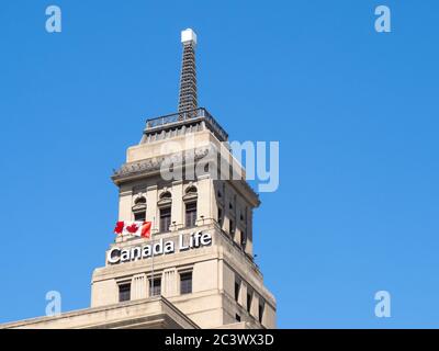 Toronto Kanada 14. Juni 2020; das historische Canada Life Gebäude Wetterfeuer mit einer kanadischen Flagge, die auf einem tiefblauen Himmel fliegt Stockfoto