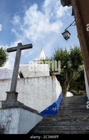 Blick auf alte Steinkreuz und gepflasterten engen Straße in Obidos Dorf Portugal Stockfoto